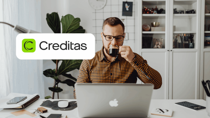 Hombre tomando una taza de café mientras trabaja en su computadora portátil con el logo de Creditas
