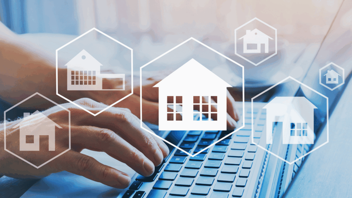Manos de una persona digitando en un teclado de laptop, con íconos de casas en hexágonos flotando sobre la pantalla. La imagen simboliza la inversión digital en bienes raíces y es ideal para ilustrar el concepto de FIBRAs para principiantes, mostrando cómo se puede invertir en propiedades a través de plataformas en línea.