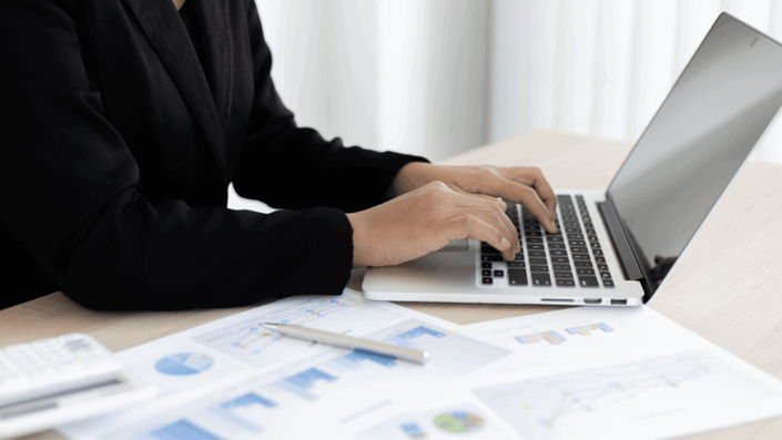Persona trabajando en una computadora mientras revisa gráficos financieros, simbolizando la gestión financiera efectiva para lograr la libertad financiera.